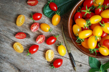 Fresh organic red and yellow cherry tomatoes in a rustic wooden bowl. food sustainability, healthy eating and vegan food.