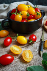 Fresh organic red and yellow cherry tomatoes in a rustic wooden bowl. food sustainability, healthy eating and vegan food.