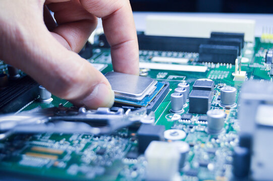 The technician is installing the CPU onto the motherboard.
