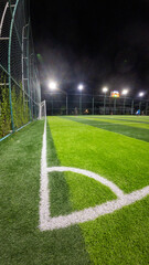 Soccer field with green grass and white line at night in Indonesia