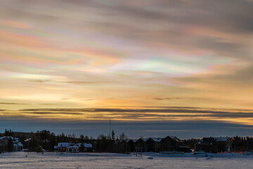 Fototapeta premium Beautiful winter sunset with rare nacreous clouds known as rainbow clouds over frozen lake Akaslompolo in Finnish Lapland.