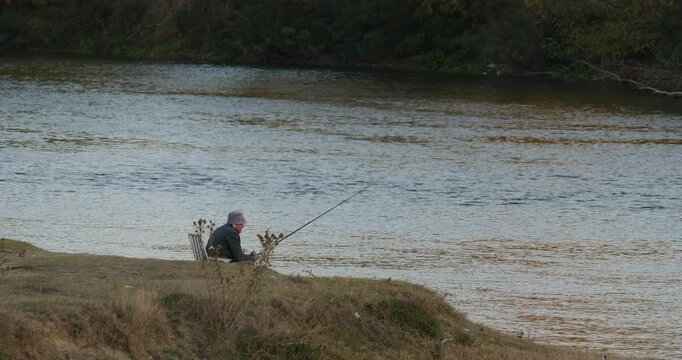 A Fisherman is Fishing on the River. He is Relaxing on a Chair 4K DCI Apple ProRes