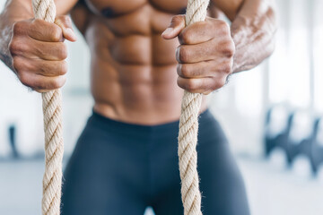 Close-up of a fit man training with a rope in a gym