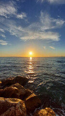 Wet limestones on the shore and a sunny path on the sea waves