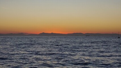 Orange sky over the sea. The hilly horizon line .