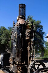 Antique Steam Engine: Old steam engine with detailed metalwork, captured against a clear blue sky.
