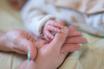 Un tout jeune nouveau-né qui tient le doigt de ses parents 