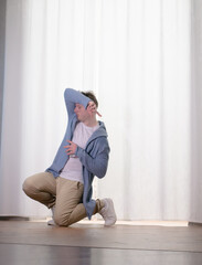 Young guy dancer in motion in a pose. A man performs a modern dance in casual clothes.