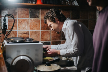 A person engaging in dish washing chores within a warmly lit kitchen atmosphere, showcasing daily life activities.
