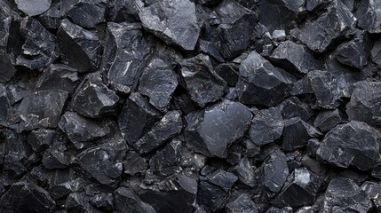 Fototapeta premium A close-up view of a large pile of black coal on a textured surface under natural light