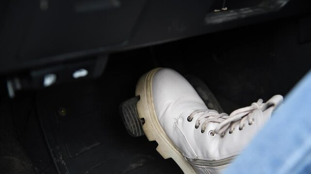 A woman confidently accelerates her vehicle, pressing the pedal down firmly. Her determination is visible as she navigates the road with skill and poise.