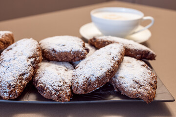 Traditional Pan dei Morti cookies featuring dried fruits, cocoa, and spices, paired with creamy cappuccino, emphasizing a cozy Italian dessert setting
