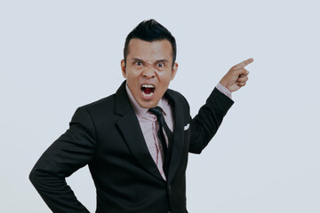 Angry Asian boss manager businessman pointing finger something to empty side, isolated over white background.