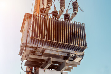 Industrial transformer against blue sky with sunlit details