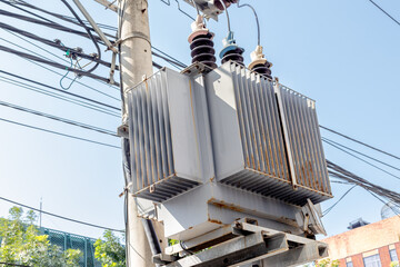 Electrical utility transformer on power pole with cables and insulators in urban setting