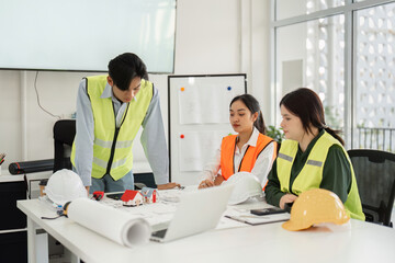 Construction team collaborating on architectural plans in modern office space with safety vests