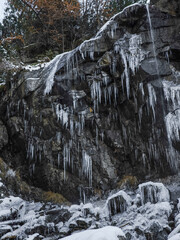 Frozen icicles dangling from rocky cliff edge in aosta, revealing winter's crystalline beauty against rugged mountainous terrain Lillaz