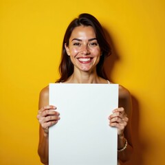 Fototapeta premium Uma mulher sorrindo segurando uma placa branca em um fundo amarelo claro, ilumina??o natural, sorriso