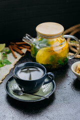Herbal citrus tea with fresh mint, lime, orange and brown sugar served in a glass teapot and cup