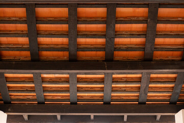 A view from inside a wooden pavilion, with dark wooden beams and terracotta roof tiles