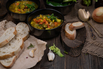 Celery, potato and carrot soup in black bowls in a rustic setting on wooden table
