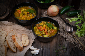 Celery, potato and carrot soup in black bowls in a rustic setting on wooden table