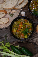 Celery, potato and carrot soup in black bowls in a rustic setting on wooden table