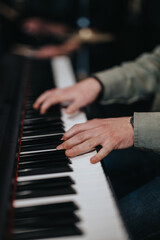 Obraz premium A musician's hands skillfully playing a piano during a band rehearsal, showcasing musical talent.