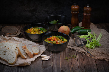 Celery, potato and carrot soup in black bowls in a rustic setting on wooden table