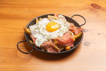 Hearty huevos rotos with crispy potatoes, jamón sizzling