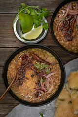 Vegan split green pea soup with tempered spices, flat breads on wooden table, copy space