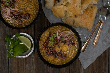 Vegan split green pea soup with tempered spices, flat breads on wooden table, copy space