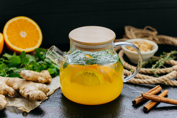 Glass teapot with citrus and ginger herbal tea, infused with fresh mint and cinnamon 