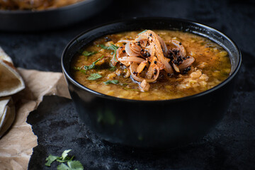 Vegan split yellow pea soup with caremelized onions, flat breads.  Black background, copy space