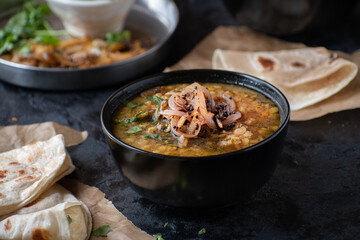 Vegan split yellow pea soup with caremelized onions, flat breads.  Black background, copy space