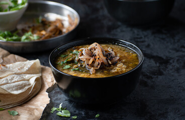 Vegan split yellow pea soup with caremelized onions, flat breads.  Black background, copy space