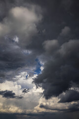 Epic dramatic storm dark grey black cumulus rain clouds against blue sky background texture, thunderstorm