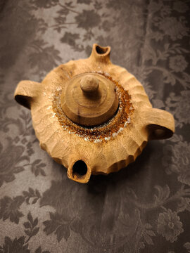 Handcrafted wooden vessel on dark floral fabric, texturing and traditional woodworking skills coffee in the grolla
