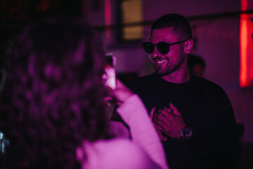 A person in sunglasses and a stylish outfit enjoying a lively party atmosphere.