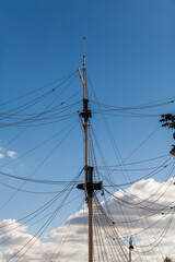 Masts of an old sailing ship against a blue sky. Old sailing boat rigging
