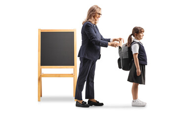 Teacher putting a book in a schoolgirl backpack