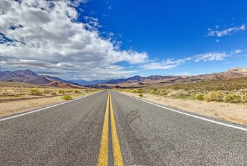 Fototapeta premium A long desert road disappearing into the distant mountains of Arizona