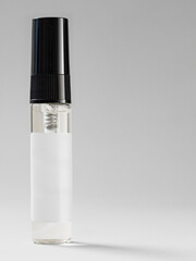 transparent glass perfume sample tester bottle with black cap on white background close up view, space for text. mockup