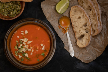 Vegan roasted pepper and tomato soup along with chiabatta bread on dark backround