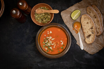 Vegan roasted pepper and tomato soup along with chiabatta bread on dark backround