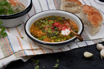 Spinach green peas and brown rice soup topped with sour cream, served in enameled bowl with home baked bread