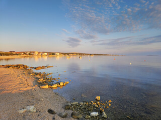Tranquil coastal landscape with calm sea and rocky beach at sunset