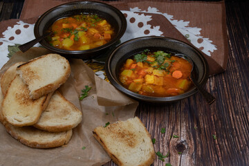 Celery, carrot and potato soup in ebameled bowls on dark table, copy space