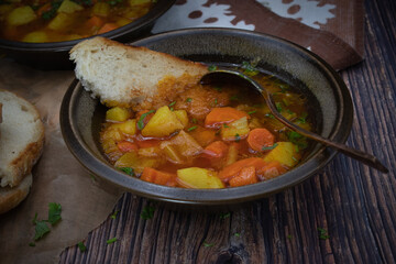 Celery, carrot and potato soup in ebameled bowls on dark table, copy space