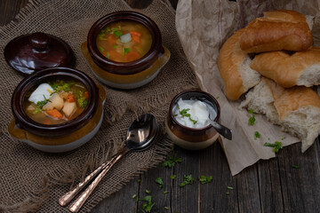 Vegatarian potato, carrot and celery soup served with cream on a rustic wooden table, along with bread